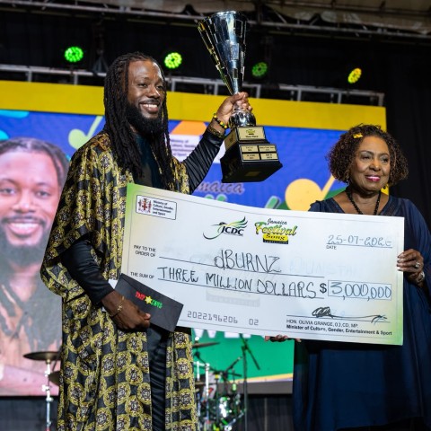 Recording artiste dBURNZ (Melbourne Douglas) (left) collects the Festival Song trophy and a cheque representing the $3 million grand prize from Minister of Culture, Gender, Entertainment and Sport, the Honourable Olivia Grange (right), after his patriotic anthem, I Love Jamaica, was crowned the winning entry in the 2026 Jamaica Festival Song Competition during the competition's landmark 60th anniversary final at the Ranny Williams Entertainment Centre on Saturday, July 25, 2026.